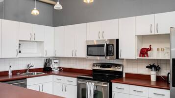 A modern kitchen with white cabinets, stainless steel appliances, and pendant lighting.