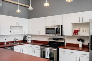 A modern kitchen with white cabinets, stainless steel appliances, and pendant lighting.