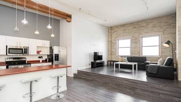 A modern kitchen with white cabinets, stainless steel appliances, and a bar stool.