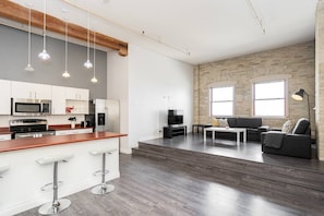 A modern kitchen with white cabinets, stainless steel appliances, and a bar stool.