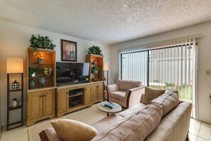 A living room with a sofa, television, wooden cabinet, and a window with blinds. - Townhome w/ Private Patio, 2 Mi to Dtwn Lakeland (Lakeland)
