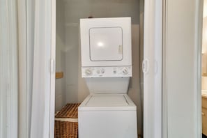 A compact laundry room with a front-loading washer and dryer, a small wicker basket, and a white door. - Townhome w/ Private Patio, 2 Mi to Dtwn Lakeland (Lakeland)