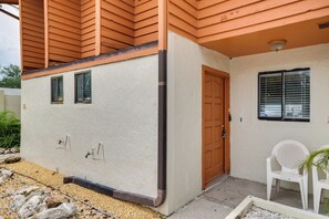 Uma casa com fachada bege, porta de madeira e janela com persianas.