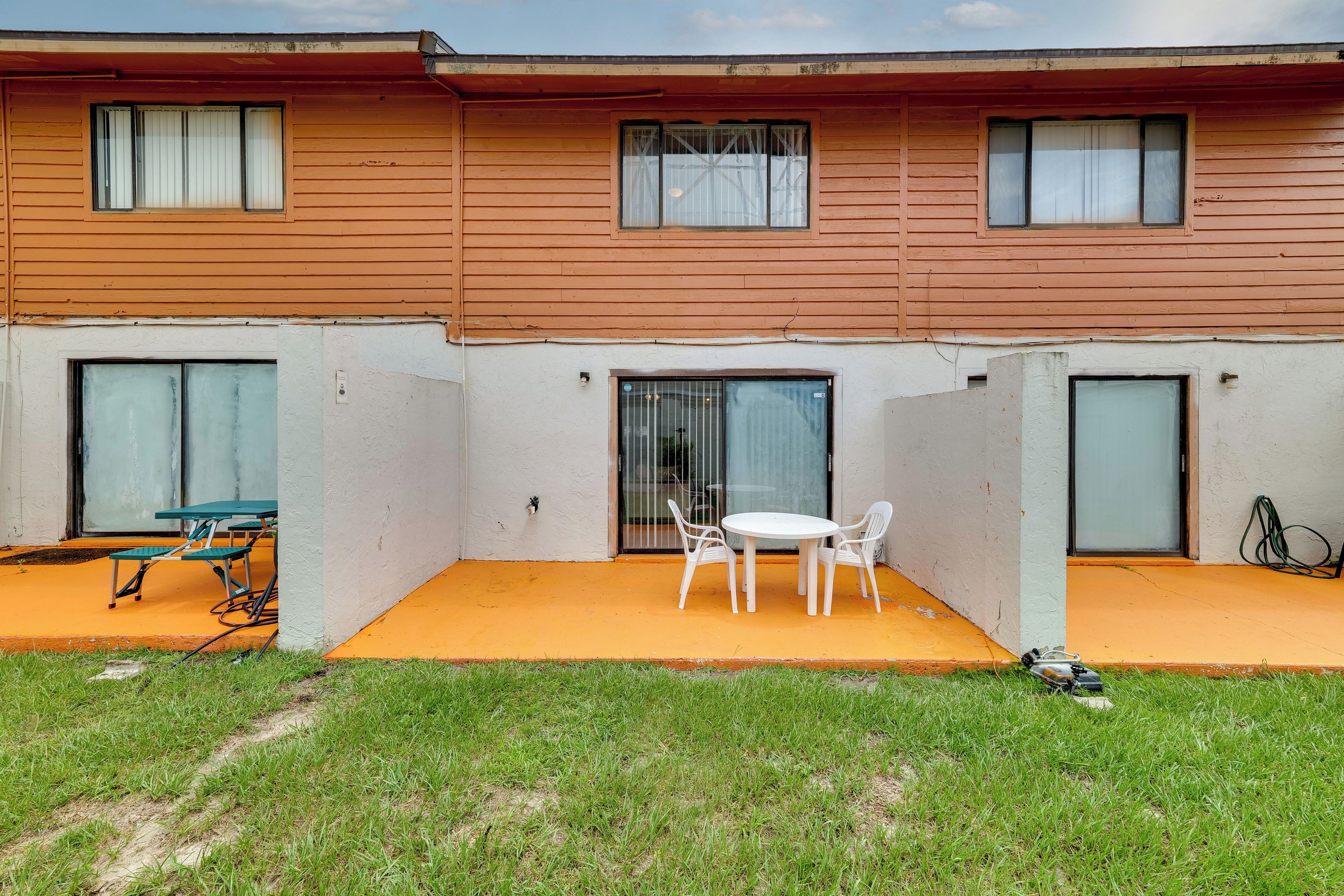 Ein zweistöckiges Gebäude mit einer überdachten Terrasse, komplett mit Tisch und Stühlen.