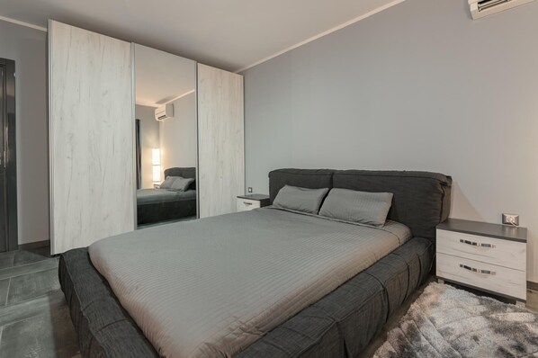 A bedroom with a bed, bedside tables, a wardrobe, and a mirror.