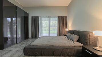 Une chambre à coucher moderne, dotée d’un grand lit, d’une table de chevet, d’une lampe et offrant une vue sur l’extérieur grâce à de grandes fenêtres.