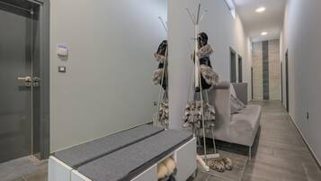 A modern interior with a bench, a coat rack, and a sofa.