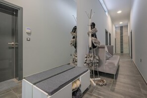 A modern interior with a bench, a coat rack, and a sofa.