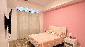 Ein Schlafzimmer mit einem Bett, einem Nachttisch und einem an der Wand befestigten Fernseher.