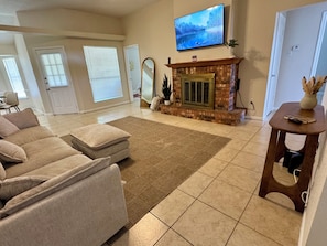 A living room with a fireplace, a television mounted above it, and a sofa.