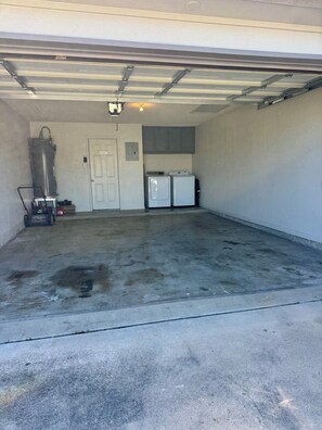 A garage with a concrete floor, a water heater, and two washing machines. - Paradise Cove! Peaceful 3bedroom plus office home in friendly safe neighborhood! (Copperas Cove)