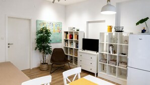 Ett modernt vardagsrum med tv, bokhylla, matbord och stolar.