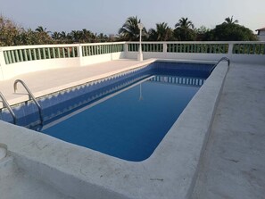 Una piscina rectangular con borde blanco y barandilla de metal.