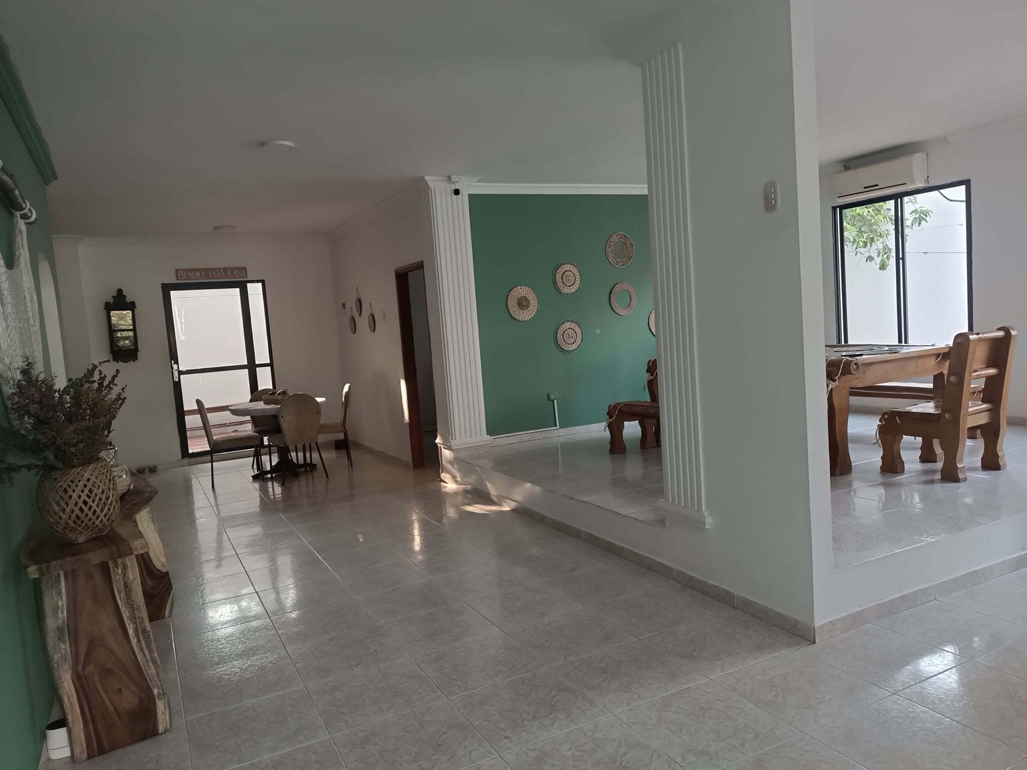 Amplia sala de estar con mesa y sillas de comedor, una escalera y vistas al exterior.