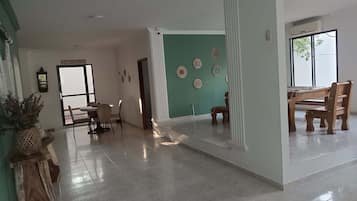 Amplia sala de estar con mesa y sillas de comedor, una escalera y vistas al exterior.