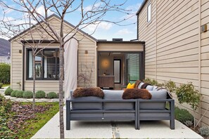 Une maison moderne avec un canapé gris placé dans le jardin avant.