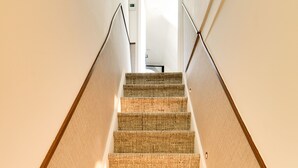 Una escalera alfombrada con barandilla que conduce a un espacio interior.