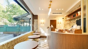 Una cafetería con mostrador, zona de estar y vistas al exterior.