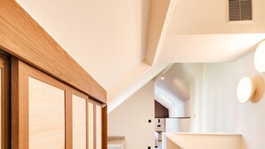 Un interior moderno con piso de madera, pared blanca y una zona de cocina con mesa y sillas.