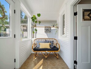 A room with a wicker sofa, a window with a view, and a door. - The Hartson  Vintage Charm on the Ben Burr Trail (Spokane)