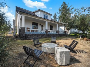 A two-story house with a covered porch, stone foundation, and a patio with outdoor furniture. - The Hartson  Vintage Charm on the Ben Burr Trail (Spokane)