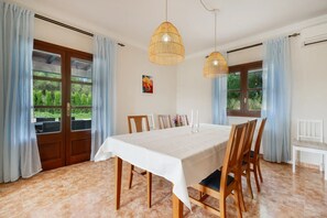 A dining area with a large table, chairs, and two hanging light fixtures. - Casa Avrelia, a country house with a garden, pool, and gym, sleeps 8, near a golf course (IB)