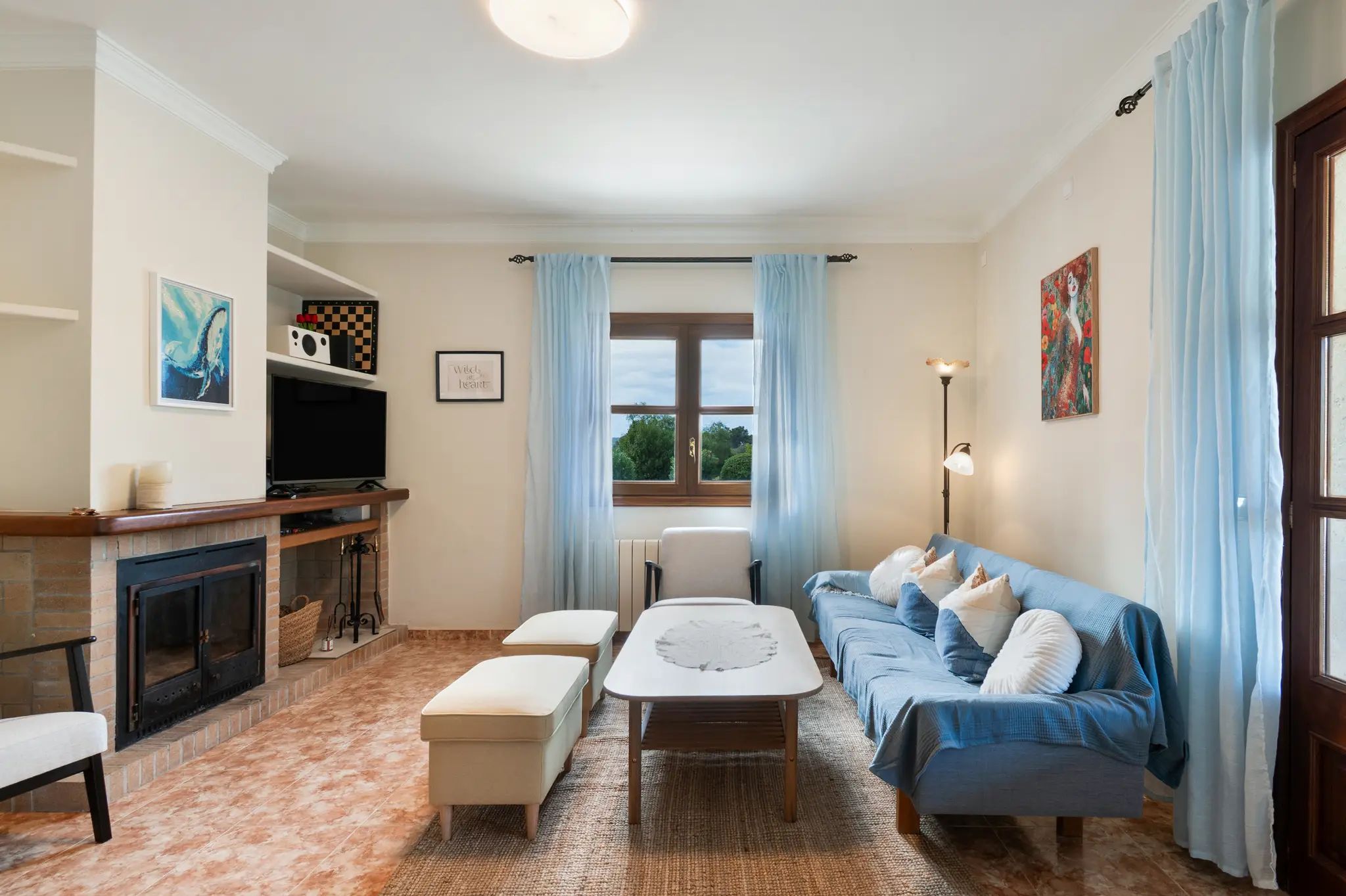 A living room with a fireplace, a sofa set, a coffee table, and a television.