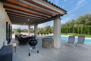 An outdoor patio with a pool, a barbecue grill, lounge chairs, and a stone fire pit. - Casa Avrelia, a country house with a garden, pool, and gym, sleeps 8, near a golf course (IB)