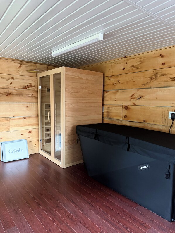 A room with wooden walls, a glass door, a black sofa, and a wooden floor.