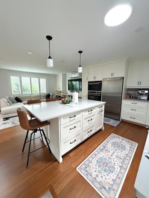 A modern kitchen with white cabinetry, a central island, and a stainless steel refrigerator.