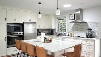 A modern kitchen with white cabinetry, stainless steel appliances, and a central island with bar stools.