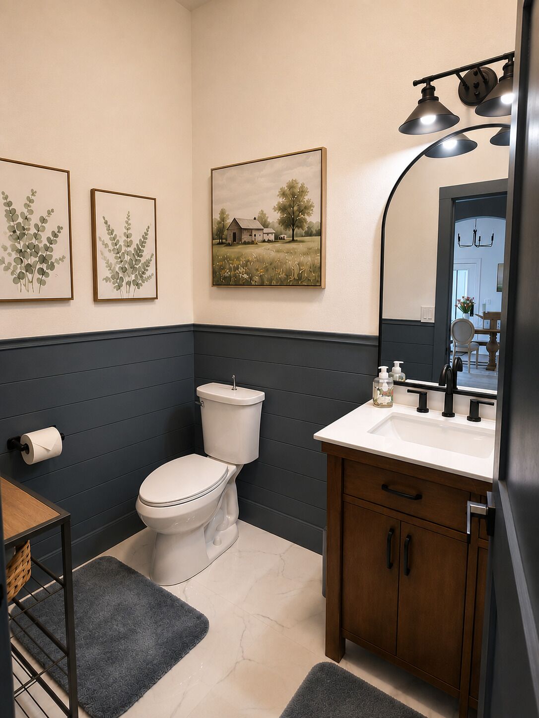 Un bagno con il water, un lavandino e un armadietto, con opere d'arte appese al muro e uno specchio.