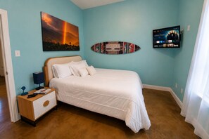 A bedroom with a bed, a nightstand, a wall-mounted TV, and a framed picture. - The Playhouse | Your Own Private Family Fun Resort (Bastrop)