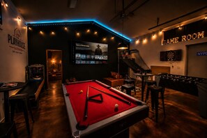 A pool table in a room with a dartboard and a foosball table. - The Playhouse | Your Own Private Family Fun Resort (Bastrop)