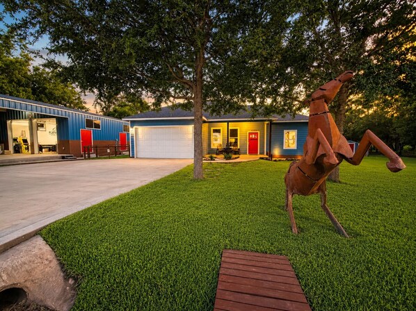 En bostadsfastighet med en välskött gräsmatta, ett garage och en röd dörr.