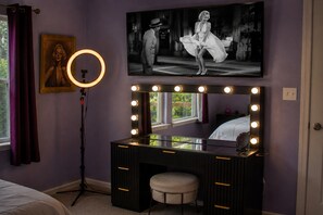 A room with a vanity, a ring light, a framed picture, and a mirror with lights. - The Playhouse | Your Own Private Family Fun Resort (Bastrop)
