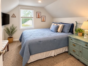 A bedroom with a bed, a dresser, a television, and a window with blinds. - 3-bedroom bungalow in welcoming downtown Fenton on the Shiawassee River. (Fenton)