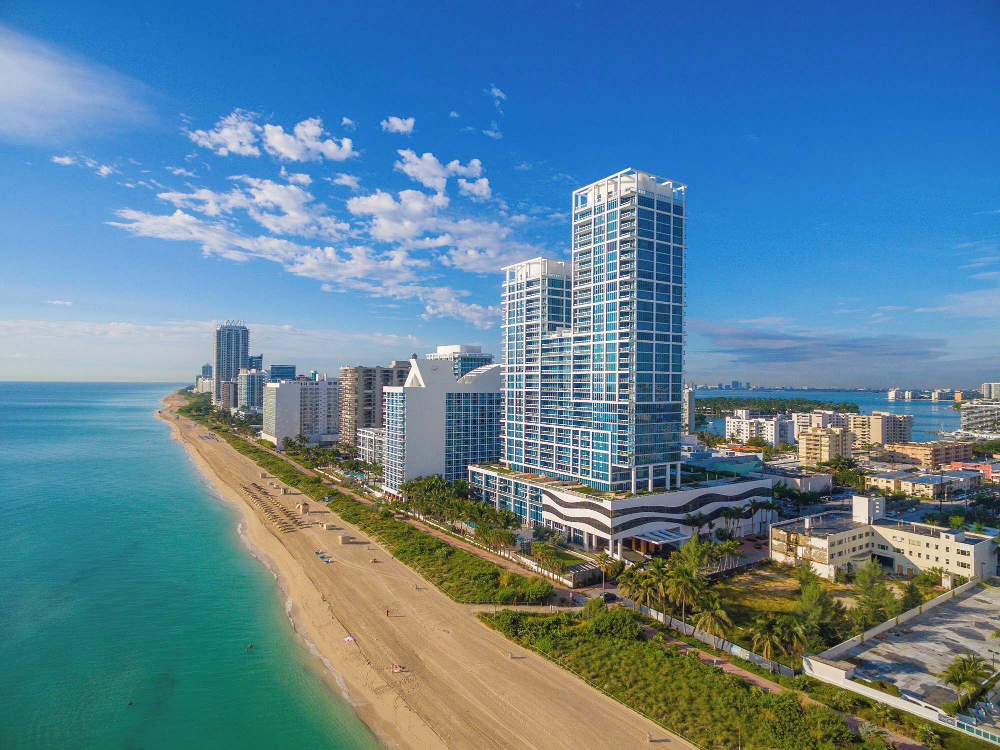 Un paysage urbain côtier avec un grand hôtel moderne, dont l’architecture est remarquable, situé juste à côté d’une plage.
