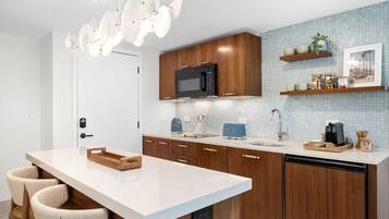 A modern kitchen with wooden cabinets, a white countertop, and a built-in microwave.