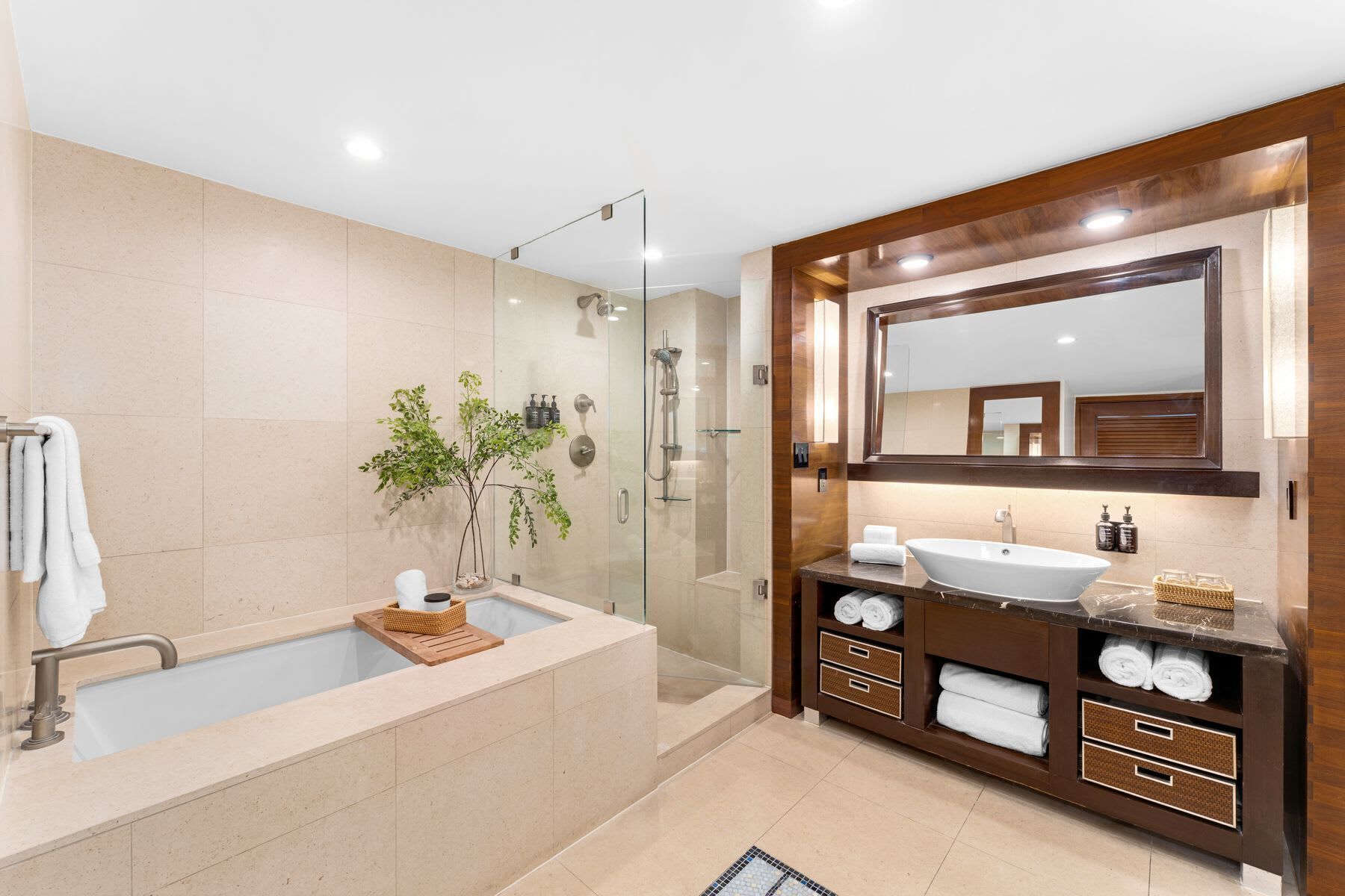 A modern bathroom with a glass-enclosed shower, a freestanding bathtub, and a vanity with a large mirror.
