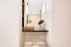 A bathroom with a vanity, a mirror, a towel rack, and a small plant.