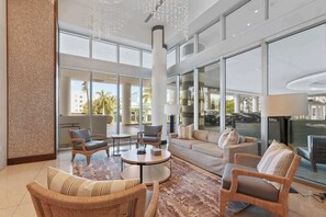 A spacious living area with a round coffee table, comfortable seating, large windows, and a view of the outdoors.