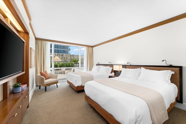 A hotel room with a large bed, a desk, a chair, and a TV.