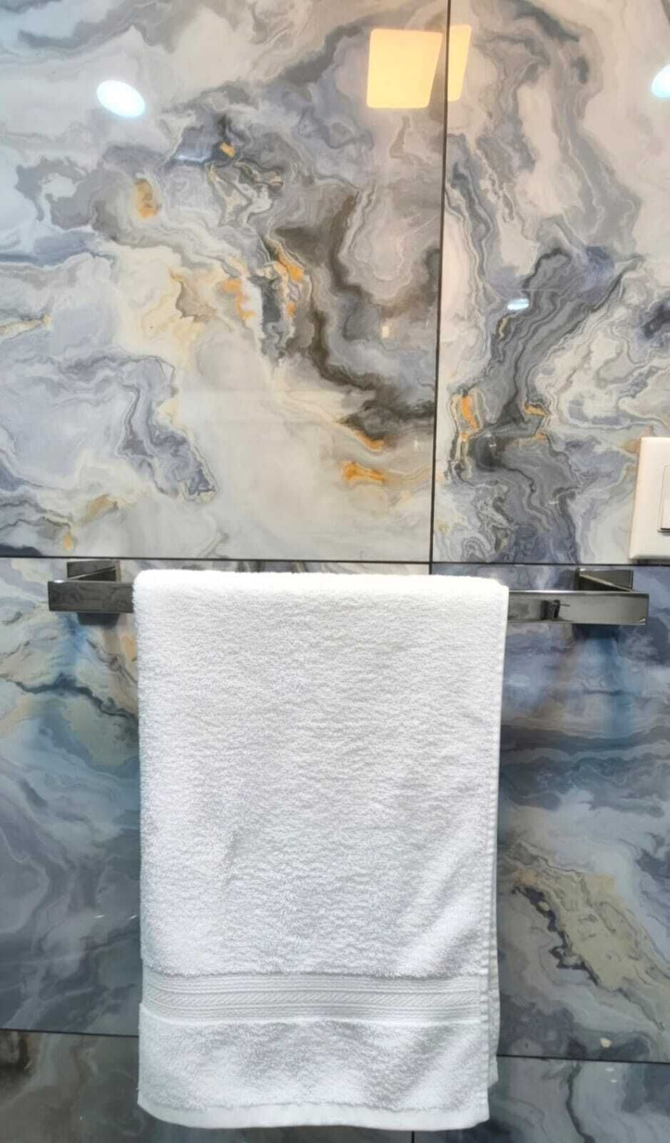 A bathroom with a marble wall and a white towel hanging on a towel rack.