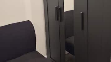 A room with a dark-colored wardrobe, a matching bench, and a wooden floor.