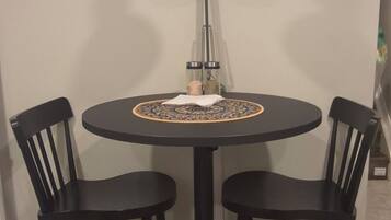 A round dining table with four black chairs, a black table lamp, and a decorative table runner.