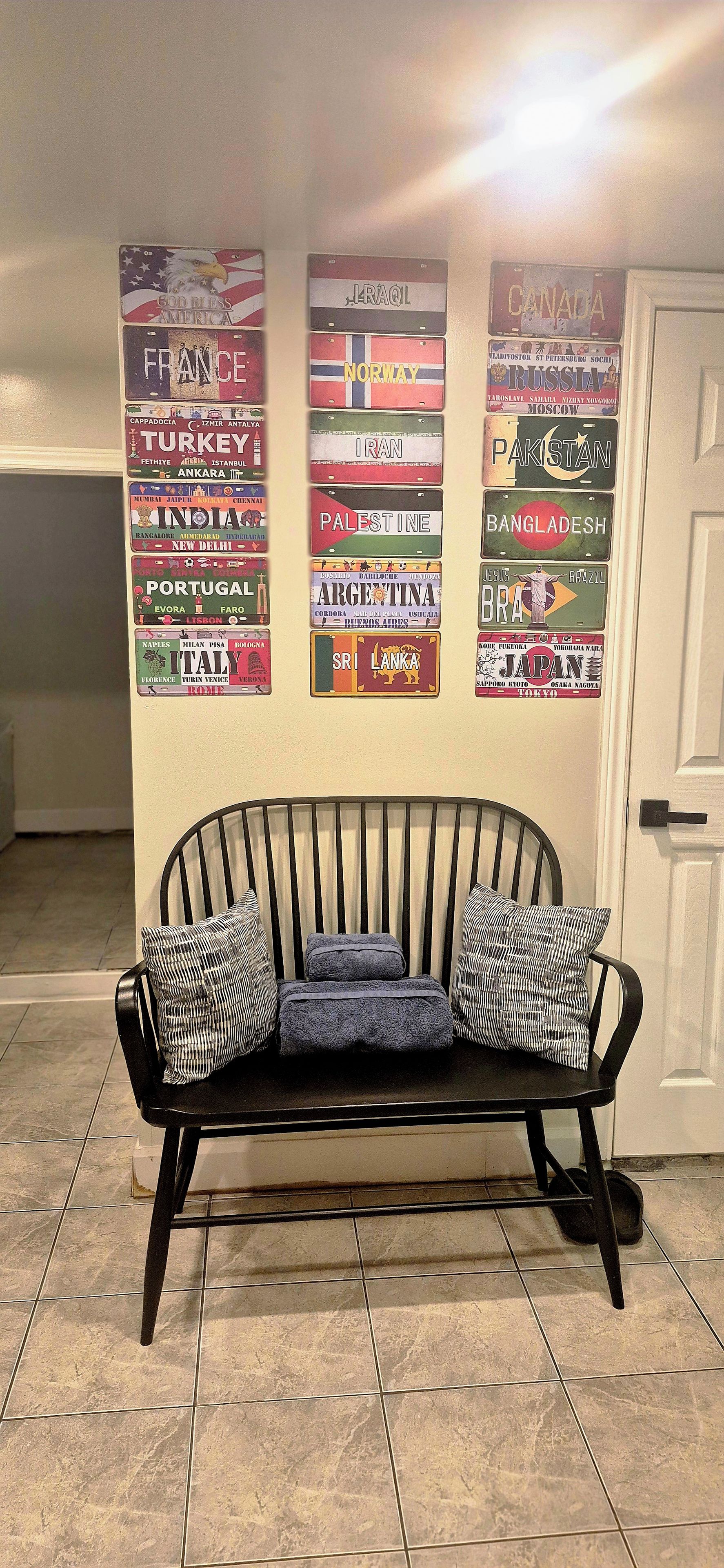 A black sofa with patterned cushions in a room with a tiled floor.