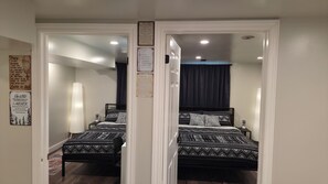 A mirrored room with a bed, a nightstand, and a wall with religious posters.