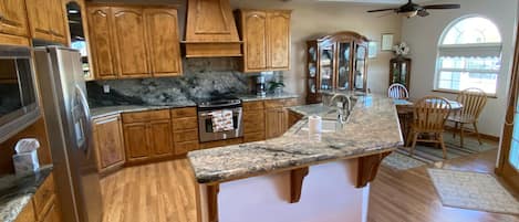 A kitchen with wooden cabinets, granite countertops, a stainless steel refrigerator, and a built-in oven.