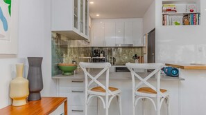 A modern kitchen with white cabinets, a green bowl on the counter, and a coffee machine. - Samsara in Suffolk Park (Suffolk Park)